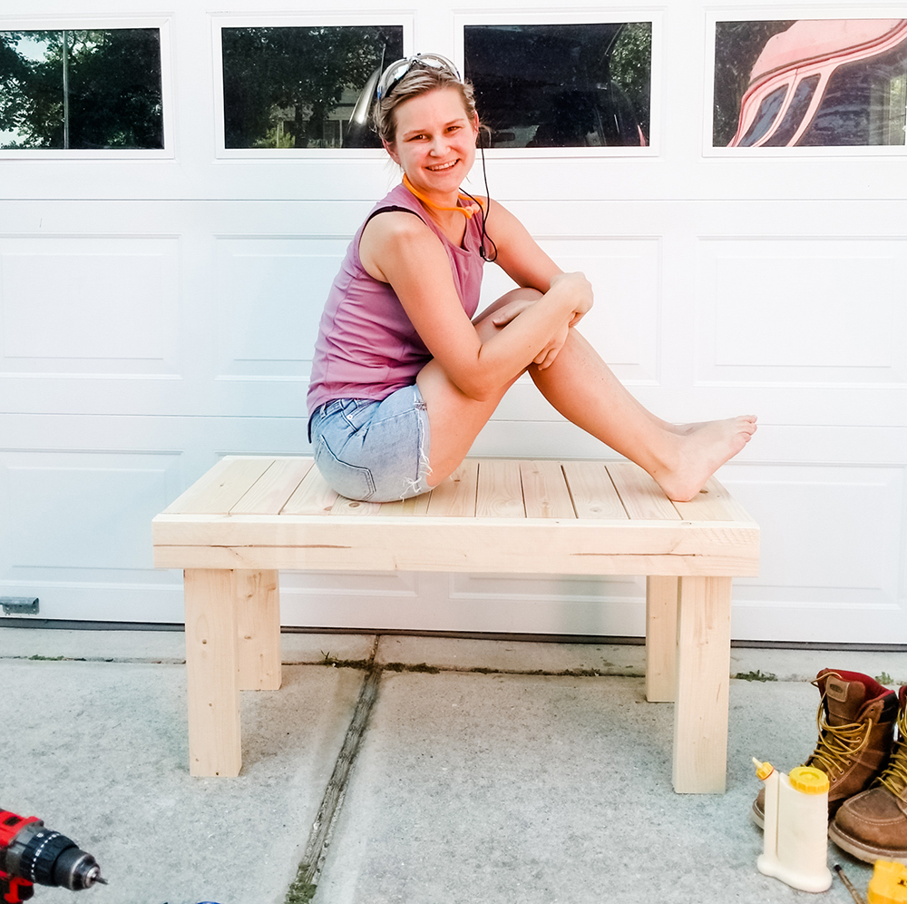 Emilee sits on a table she made
