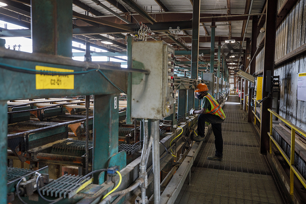 West Fraser employee watches boards move through the mill