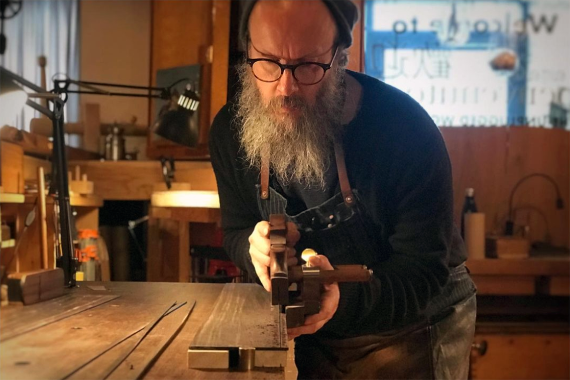 Tom Fidgen using a hand tool to cut wood