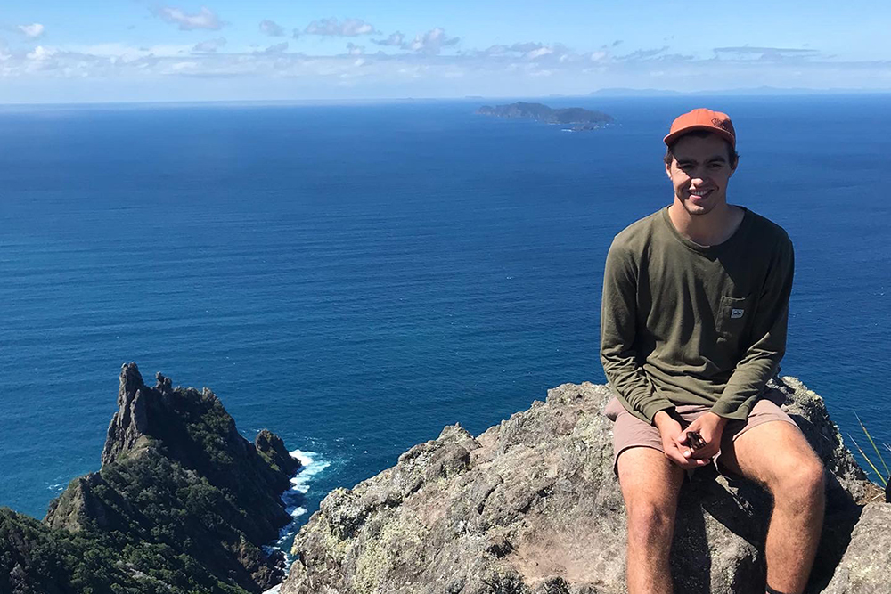 Patrick sitting on a rock with water view in the background