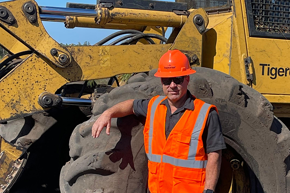 Logger with heavy equipment and safety gear