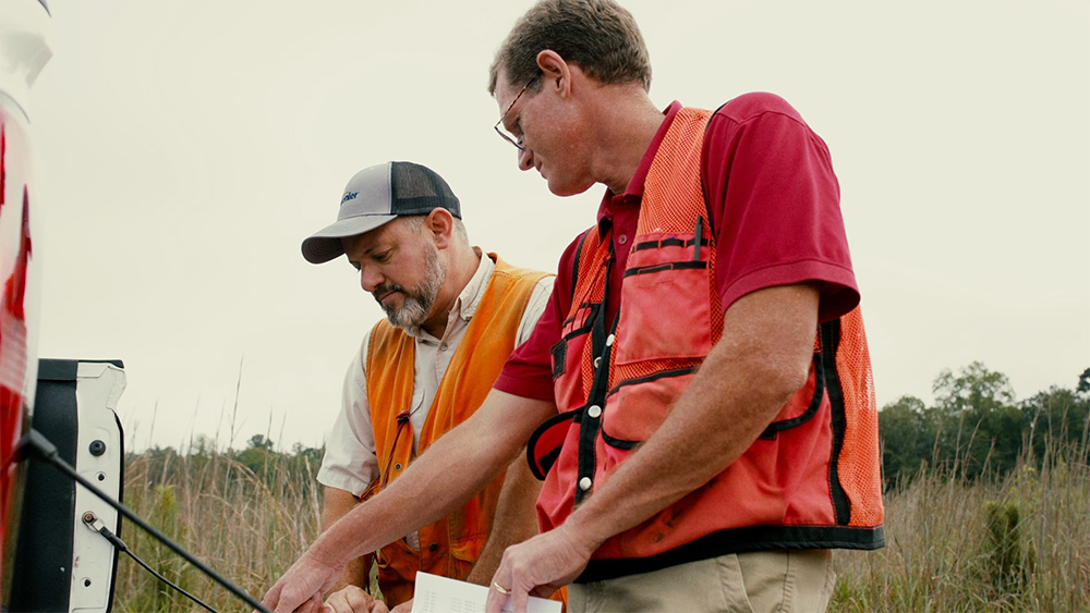 Men looking at a map on a tailgate in a young forest