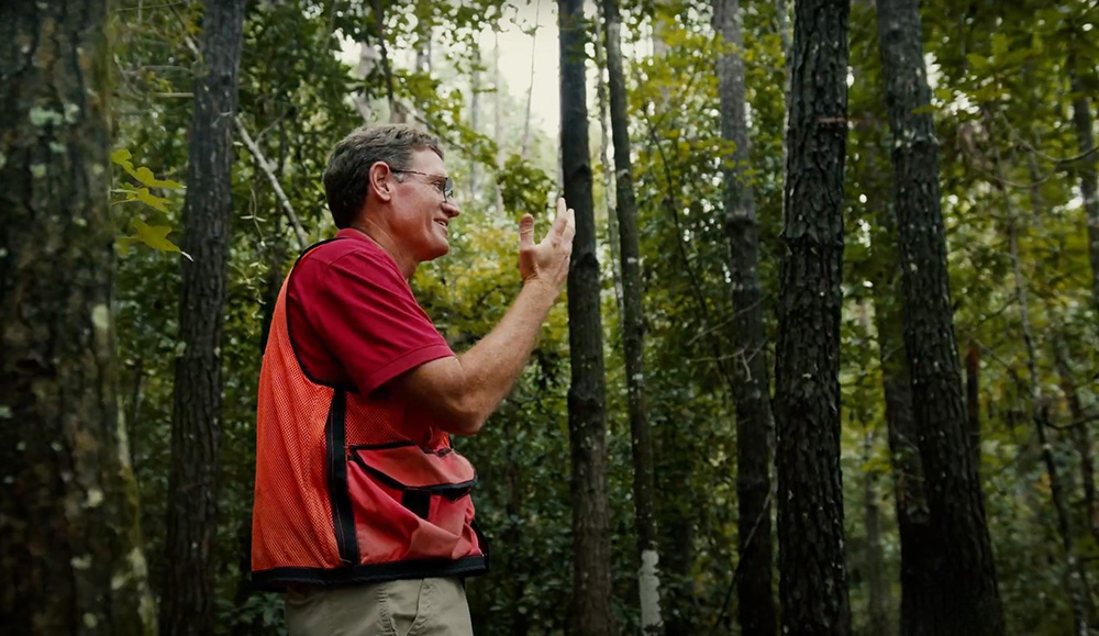 Phillip standing in the woods having a laugh with someone off camera