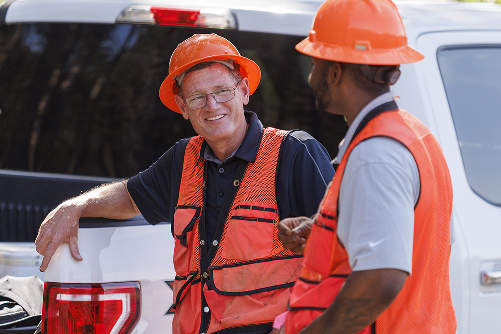 Two men talking while leaning on a pickup truck