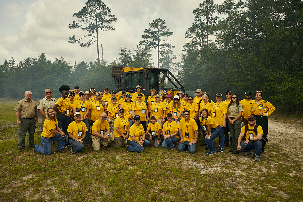 People in yellow tour tshirts pose for a photo near the forest